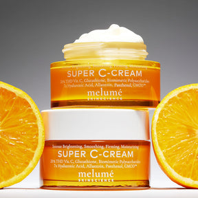image mood of two Melume Skinscience's super c-cream stacked on top. The top super c-cream is opened showing the texture. Next to both super c-cream are oranges.